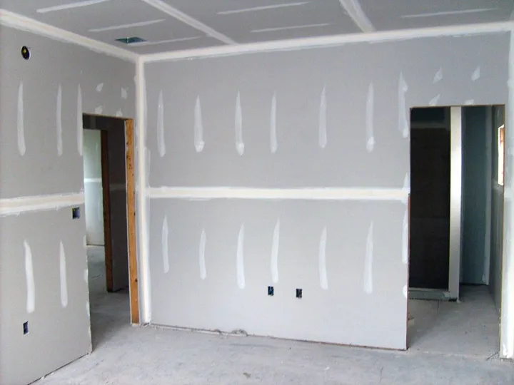 Drywall panels screwed to wall studs with screws visible, the hang stage of a job in progress